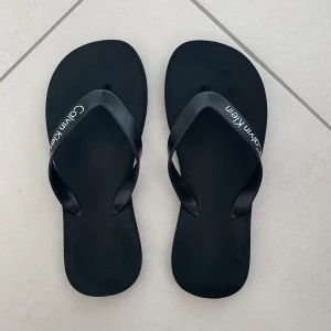 Calvin Klein Flipflops - Ett par jättefina/sköna flip-flops från Calvin Klein. Köptes på Calvin Klein i Kanada för ca 249 SEK men säljer för 150 kr. Strl 38 men passar även 39🤍🤍