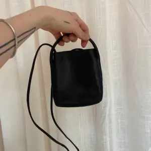 Mini väska för mobil eller dåligt. I äkta läder. Stängning med magnet och två fack inuti. Längre band för att ha väskan hängandes runt kroppen. 