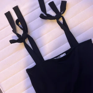  Justerbart Linné i axlarna -  Svart linne från NA-KD Som går att knyta armarna på. Köpt second hand.