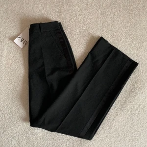 ZARA svarta kostymbyxor med glans - Stilrena kostymbyxor som passar såväl till vardags som till fest. Glansig rand på respektive sida av benen. Tillhörande kavaj finns i en annan annons. 🌹 Nya med tags kvar. Utan anmärkning.