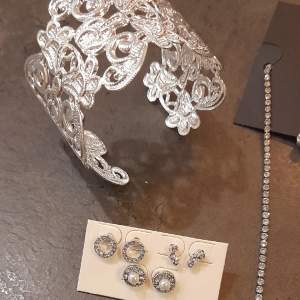Smycken i silver och strass i nyskick.  Halsband, armband, hårsmycke, ringar och flertalet örhängen. Estimerat värde xa 550kr.