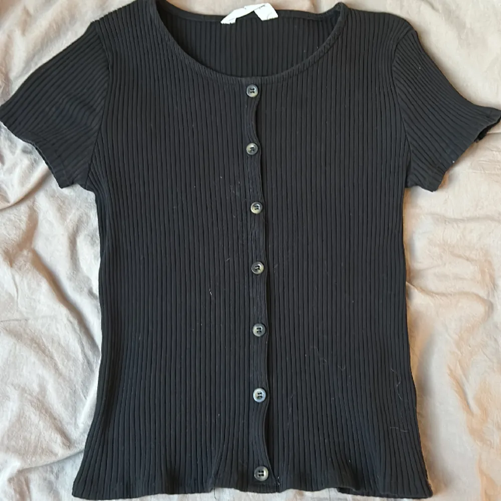 Ribbad svart tröja åtsittande men väldigt bekväm med lite knappar på fram sidan och knappt använd . T-shirts.