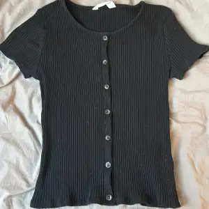 Ribbad svart tröja åtsittande men väldigt bekväm med lite knappar på fram sidan och knappt använd 