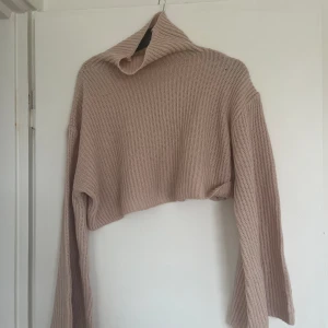 Stickad tröja  - Här har vi en fin stickad tröja som ger en mysig färg av baby rosa. Har en karga som gör att det blir varmt runt halsen. Den är lite kort så de blir en typ av magtröja 