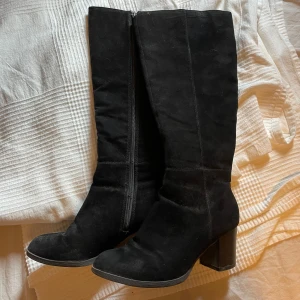 Klackar  - Klackar med svart mocka liknande tyg. Fint skick. Slutar nedanför knäna. 