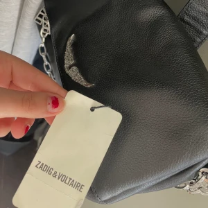 Zadig & Voltaire -axelremsväska  - Höjd:22cm, Långd:30cm, Vidd:6cm,Handtag:34cm (Väskan är av skinn). Hjälper min syster med att sälja väskan då hon köpte den i en annan modell, väskan är i helt nytt skick. Skriv privat för fler bilder eller för frågor.