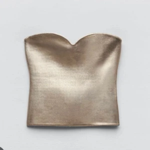 Guldig topp Zara - Säljer denna sjukt snygga och populära topp ifrån Zara som är helt utsåld på hemsidan. Den är endast använd en gån och är som i nyskick. Den är i storlek L men eftersom den är väldigt liten i storleken skulle jag säga att den passar S/M.
