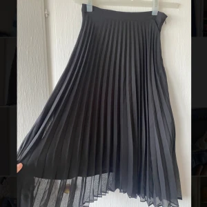 Plisserad kjol - Svart plisserad kjol från Vero Moda i storlek XS. Vad lång för mig som är 157 cm.