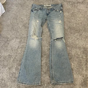 Lågmidjade bootcut jeans - Säljer dessa ljusblåa lågmidjade bootcut jeans med slitningar. Midjemått: 76cm Innebenslängd: 78cm. Har ingen bild på då de är för små. Har du någon fråga är det bara att höra av dig🫶🏻