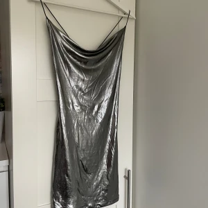 Satinklänning - Kort. Korsad i ryggen. Silver. Storlek xs, från H&M men köpt på tise. Aldrig använd men prislappen har tagits bort. 
