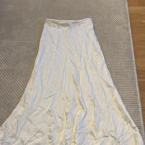 Satinkjol  - Vit satinkjol i strl 32. Något tajt i midjan.