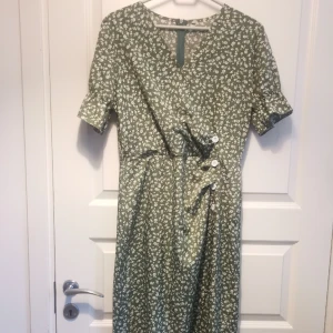 Titta vilken fin klänning  - Lite rockabilly-stil, assymeyrisk, snyggt skuren med liten puffärn och dragkedja bak i ryggen. Nyskick 