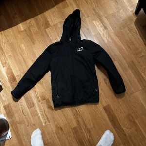 Ea7 jacka - Svart Armani jacka, bra kvalitet men det är ett hål i högra fickan men det syns inte passar om du är runt 170. Hör av dig för mer info!