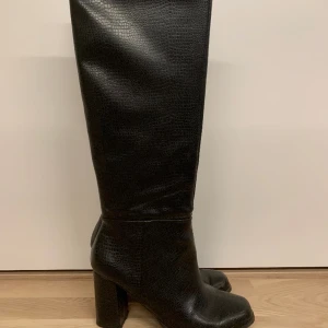 Klackstövlar - Svarta knähöga stövlar med 8cm klack i konstläder. Är i nyskick, nypris är 1000kr. Fler bilder går att få. Eventuella frågor är det bara att höra av sig med.