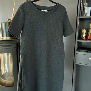Kort klänning med stickad struktur i en fin gråblå färg. Väldigt mjuk och skön med lite stretch. Storlek XS. Rökfritt hem, dock ej djurfritt.