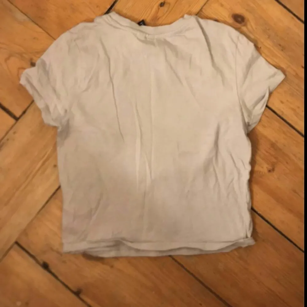 En jättefin ljusgrå croppad t-shirt (babytee) med tryck från H&M endast använd 2 gånger och säljer därför den 💕. T-shirts.