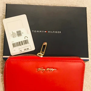 Tommy Hilfiger Dam Plånbok - Helt ny, original med pris lapp! Oanvänd. Lång 16cm,bred 10cm,tjock 2,5cm.