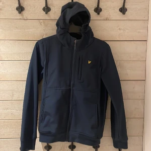 Lyle & Scott  - Strl 164, jackan är i nyskick pågrund av fördöjning av returneringen under en order så den har inte använts Jackan är en soft Shell perfekt inför våren särskilt när det regnar pågrund av dess vattentäthet. Dm för mer frågor eller bud
