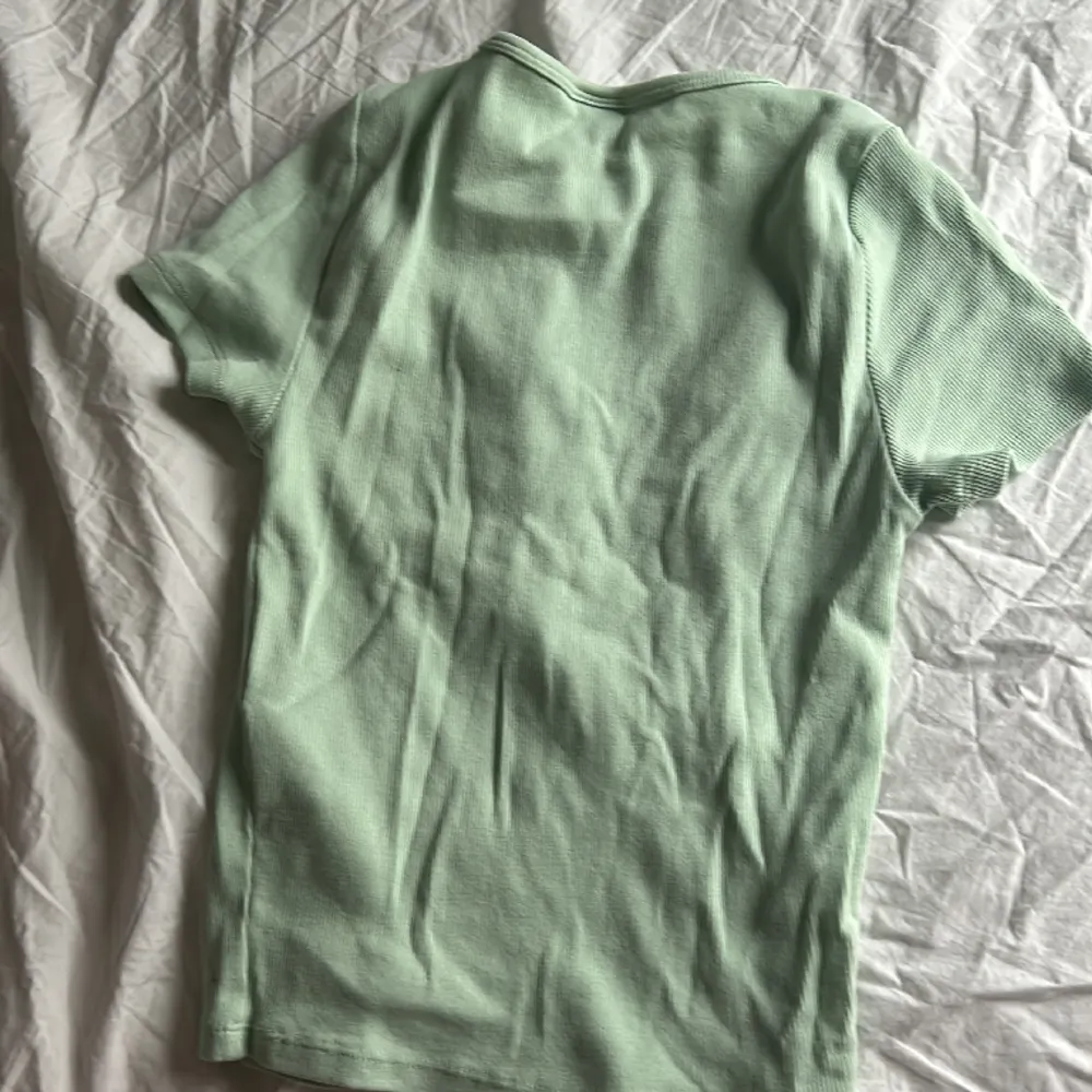 En grön topp med kort armar och lite urringad från Gina tricot. T-shirts.