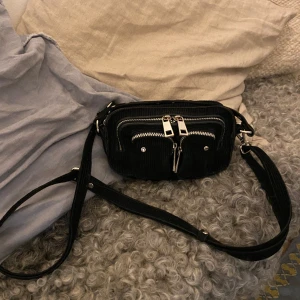 Äkta NUNOO väska - Liten svart väska! Perfekt till mobil, plånbok, nycklar mm.  Använd men ändå i fint skick.  Saknar en bit av en dragkedja (se sista bilden).  Köpt för typ 800, säljer för 150 pga dragkedjan och använd ❤️ 
