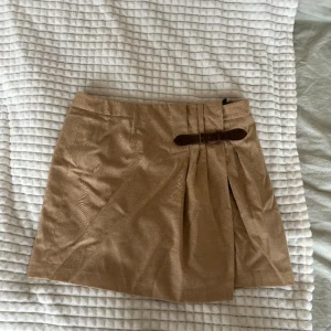 Brun Tommy Hilfiger kjol - Brun äldre Tommy Hilfiger kjol fint skick storlek 10 uppskattar till storlek 38. Finns knappar på kjolen så man kan ”spänna” ut den ifall det behövs. Aldrig använd