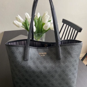 Guess väska  - Väska från guess i fint skick! Medföljer en mindre väska i. Har använt den till skolan och man får gott och väl plats med dator, block osv! Enda tecknet på användning är nötning på banden som kan ses på sista bilden, i övrigt ser den oanvänd ut! 