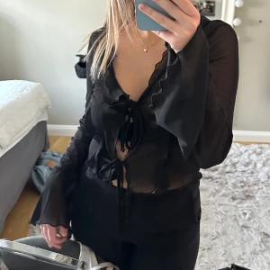 Svart festtopp - Svart festtopp som är lite genomskinlig med volanger och vida ärmar