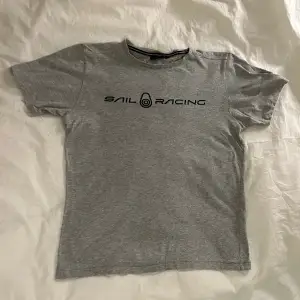 Denna T-shirt är av märket Sail Racing. T-shirten har används varsamt och är i bra skick. Säljer detta plagget eftersom den har blivit för liten. Plagget har storleken 170 men passar för folk som bär XS