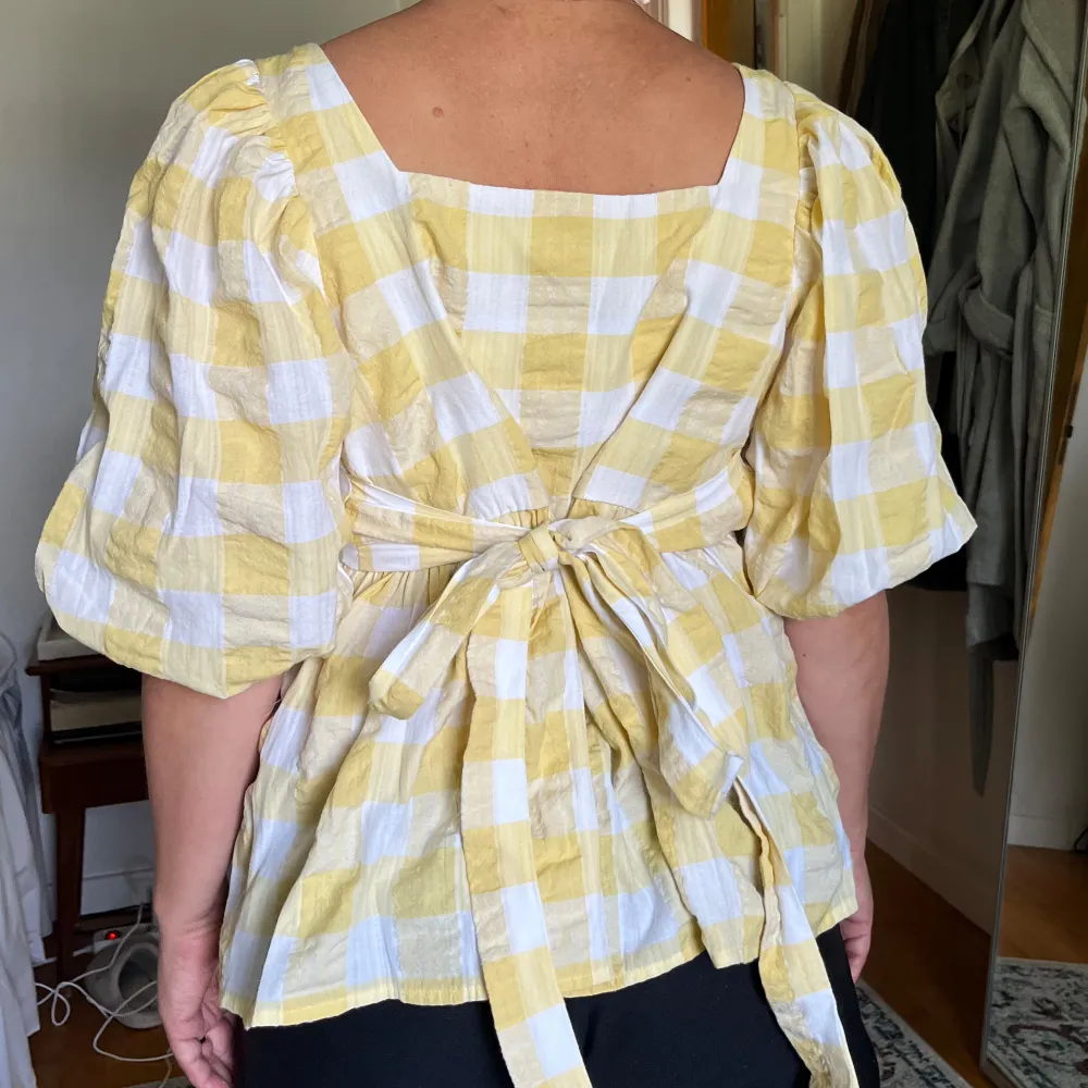 Rutig blus med puffärmar och rosett där bak. Fint skick. Storlek M men kan också passa S 💛💛. Puserot.