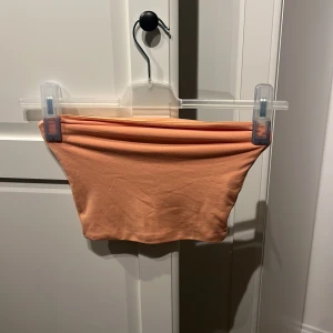 Persikofärgad tubtopp från BikBok - En enkel och stilren persikofärgad tubtopp från BikBok. Toppen är ärmlös och har en tight passform.