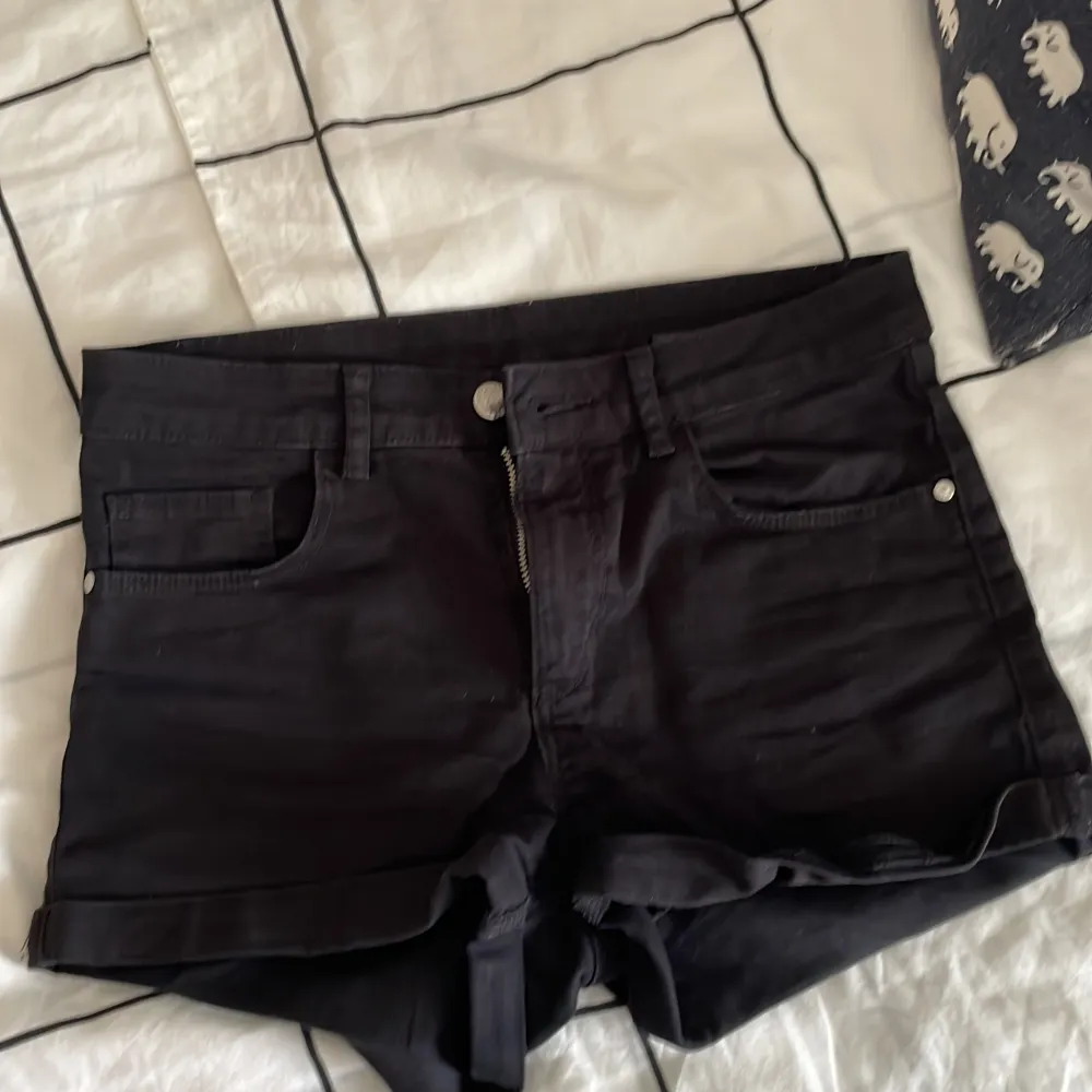 Säljer ett par svarta jeansshorts från H&M i storlek XS. De är lågmidjade och har en dragkedja och knapp framtill. Shortsen har två fickor fram och två bak, samt uppvikta benslut. Perfekta för sommaren! 🌞. Shorts.