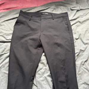 Svarta kostymbyxor från BikBok - Ett par svarta kostymbyxor från BikBok i storlek 42. Byxorna har en klassisk design med hällor för bälte och fickor både fram och bak.