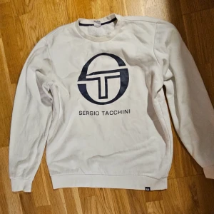 Sergio tachinni - Sergio Tacchini Tröja - Medium Märke: Sergio TacchiniStorlek: MediumFärg: Vit med marinblå loggaMaterial: Högkvalitativ bomullsblandning, som garanterar komfort och hållbarhet Skick: Utmärkt, varsamt använd utan synliga slitage Design: klassisk