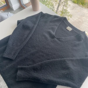 En svart fin stickad tröja  - Jag säljer en jätte fin svart tröja från hm med urringning och 2 slittar på varsin sida av tröjan. Den är i storlek xs men den har en lite större passform så den är säkert jättefin på många!