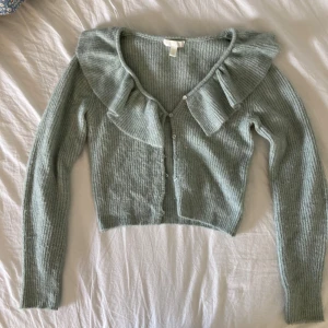 Grön kofta - Stickad, mjuk kofta från H&M, med volang högst upp. Använd ett fåtal gånger. 