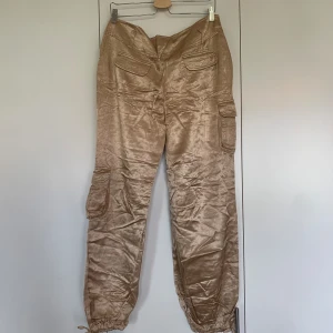 Helt ny byxa  - Champagne färgade glansiga byxor Helt nya med lappen kvar  