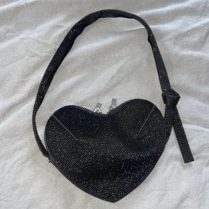 Hjärtformad väska - Svart glittrig hjärtformad väska från Zara, axelremmen är defekt men går säkert att limma fast. Väskan har ett innerfack och det finns inga fläckar eller liknande på samt i väskan.