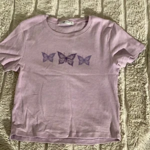 En fin somrig lila fjäril tröja  - En tröja med storleken s, från new yorker. Den tröjan är använd få gånger. Bra skick men har en liten märke nere som inte syns så mycket  