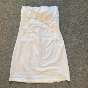 Vit kortklänning  - Vit kortklänning med en liten dragkedja bak. Det är dubbel tyg vid bysten.