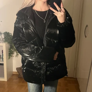 Jacka - Säljer denna svarta glansiga jacka i storlek M (jag på bilden är XS) 😍 Den är väldigt unik i materialet och varm. Från märket ”House”. Lik Calvin Klein jacka. Toppskick! Klicka gärna på köp nu 👇🏻