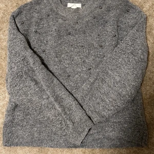 Stickad tröja HM - Säljer denna grå stickade tröjan med pärlor från hm. Säljer då den för att den har blivit för liten för mig. Skriv om ni undrar något.