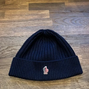 Moncler mössa - Moncler Grenoble inköpt på NK i Göteborg. Mössan är knappt använd och i mycket bra skick. PM för bilder på tags eller andra vinklar. Nypris 1800.
