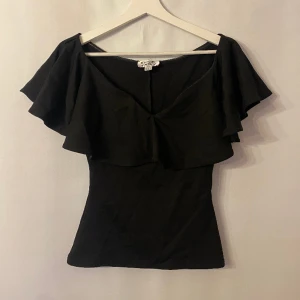 Topp med volang - Off shoulder topp med volang. Märke: Unique vintage. Storlek: S