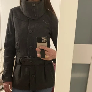 Kappa - Kappa i storlek 38 .dragskedja framme och stora knappar upp till halsen .höftbälte   Med två knappar .två bröst fickor och två höft fickor .tål kyla , kappa klara av kylan 