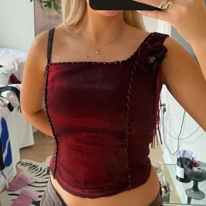 Y2k top - Vinröd y2k korsettop köpt secondhand, tyvärr för liten för mig men oootroligt söt med en blomma på🌺