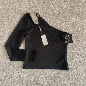 Nelly cut-out topp / one shoulder topp  - Snygg topp från Nelly med cut-out detaljer och one-shoulder. Ny med tags kvar.