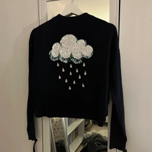 Tröja med halvpolo - En mörkblå tröja med halvpolo med motiv av ett regnmoln i paljetter från H&M i strl XS!💓