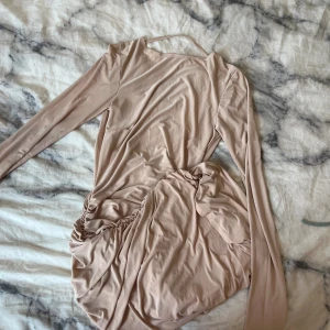 Klänning från Nelly - Jättefin beige klänning från Nelly med öppen rygg. Jätteskönt material och jättefin på!