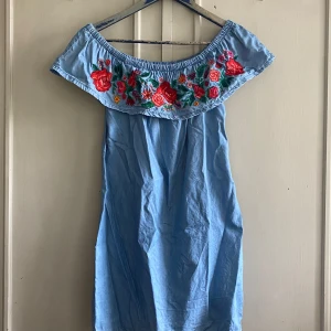 Jeansklänning med blommor  - Fin Jeansklänning med broderade blommor. Går även att använda som instoppad tröja. Storlek 36 skulle säga att den passar XS-M beroende på hur en vill att den ska sitta. Så fin och i bra skick men säljer för att den inte kommer till användning. 