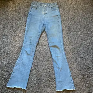Ljusblå bootcut jeans i stretchigt tyg och med ofållade benslut. Passar storlek S-M.